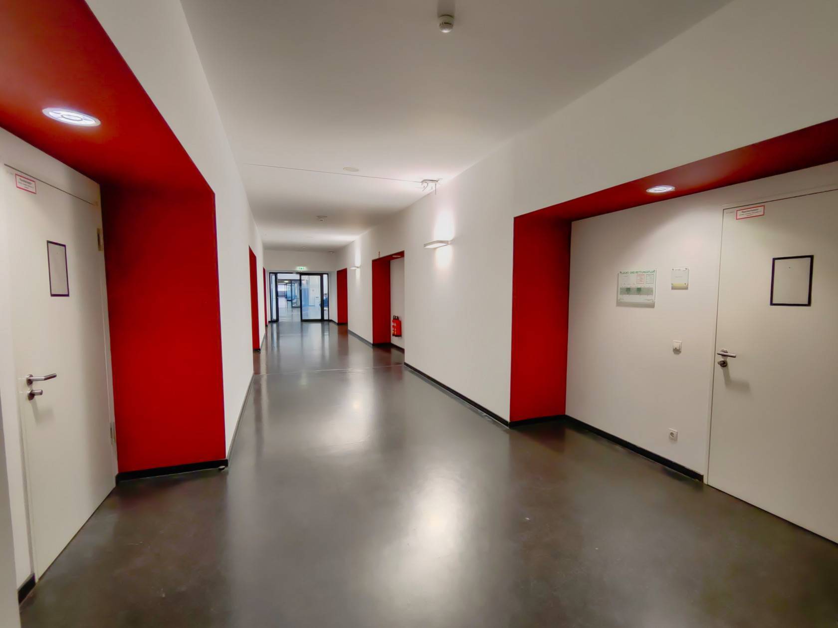Flur, links und rechts rote/weiße Wände, Türen zu den Seminarräumen