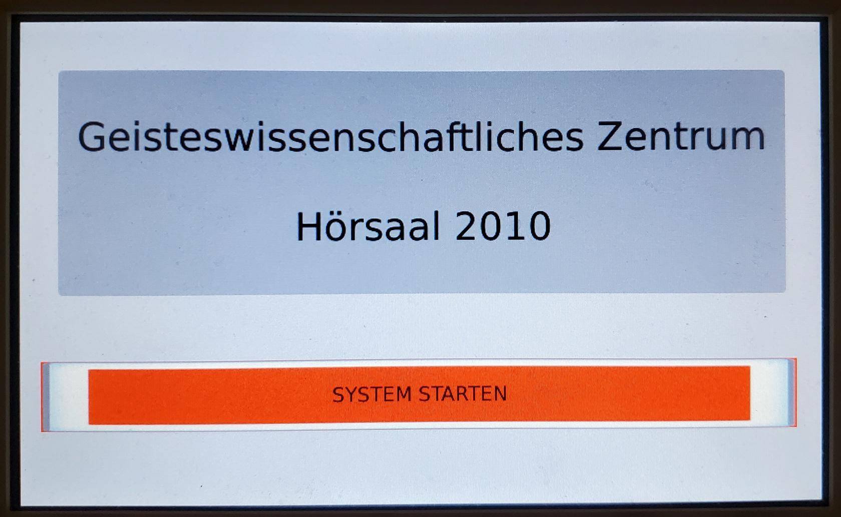 Startbildschirm der im Pult verbauten Raum- und Mediensteuerung mit Schaltfläche "System starten"