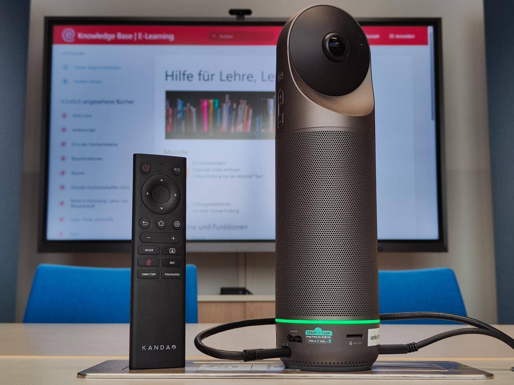 Konferenzkamera, an die zwei USB-Kabel angeschlossen sind und an der im unteren Bereich ein grüner Ring leuchtet
