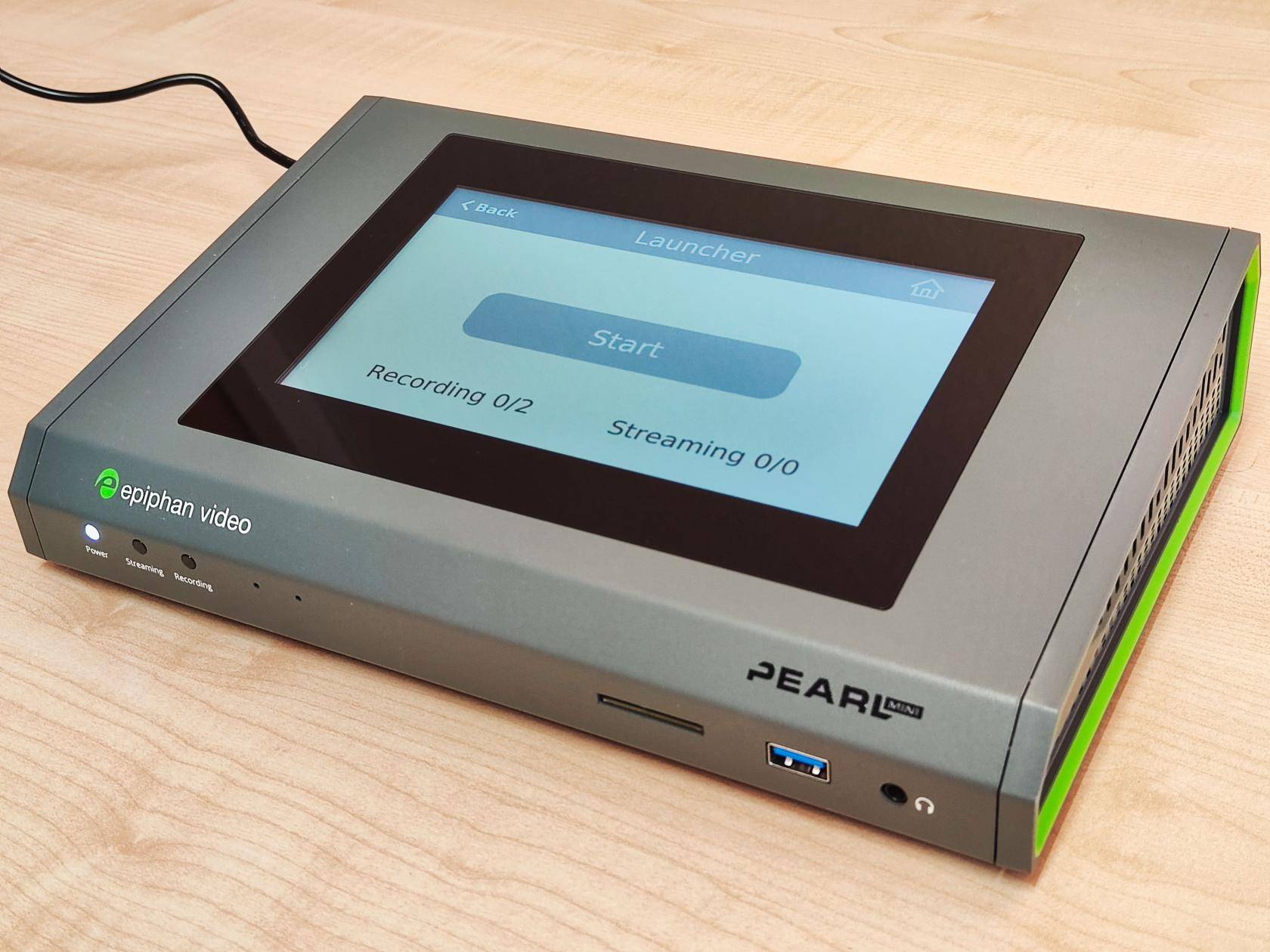 Gerät mit grünem Rahmen in Form einer flachen, leicht angewinkelten Konsole mit Touchdisplay oben, vrne LEDs für Power, Streaming und Recording sowie SD-Kartenleser, USB- und Kopferhöreranschluss