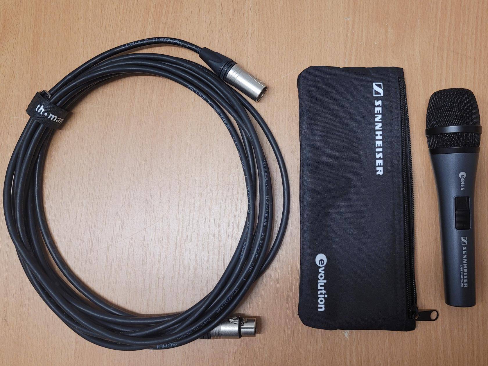 sämtliches Mikrofonzubehör nebeneinander auf einem Tisch: schwarze Mikrofntasche, Mikrofon, XLR-Kabel