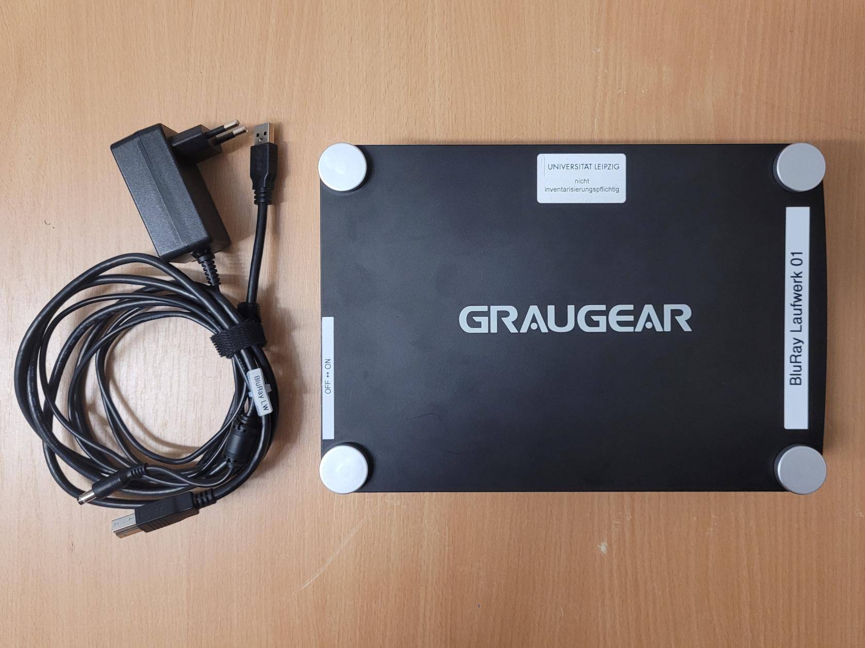 Bestandteile auf einem Tisch: externes Laufwerk, Netz- und USB-Kabel