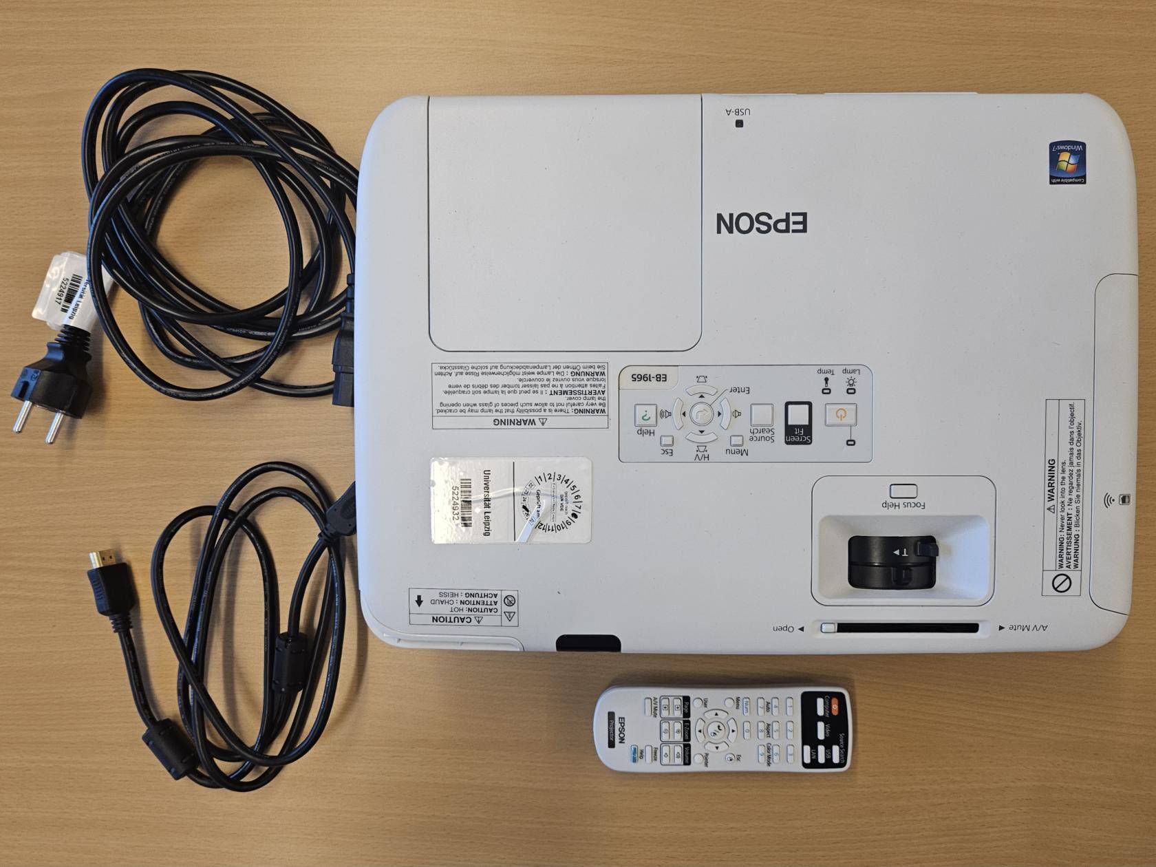 Projektor auf einem Tisch mit Stromkabel, HDMI Kabel und Fernbedienung