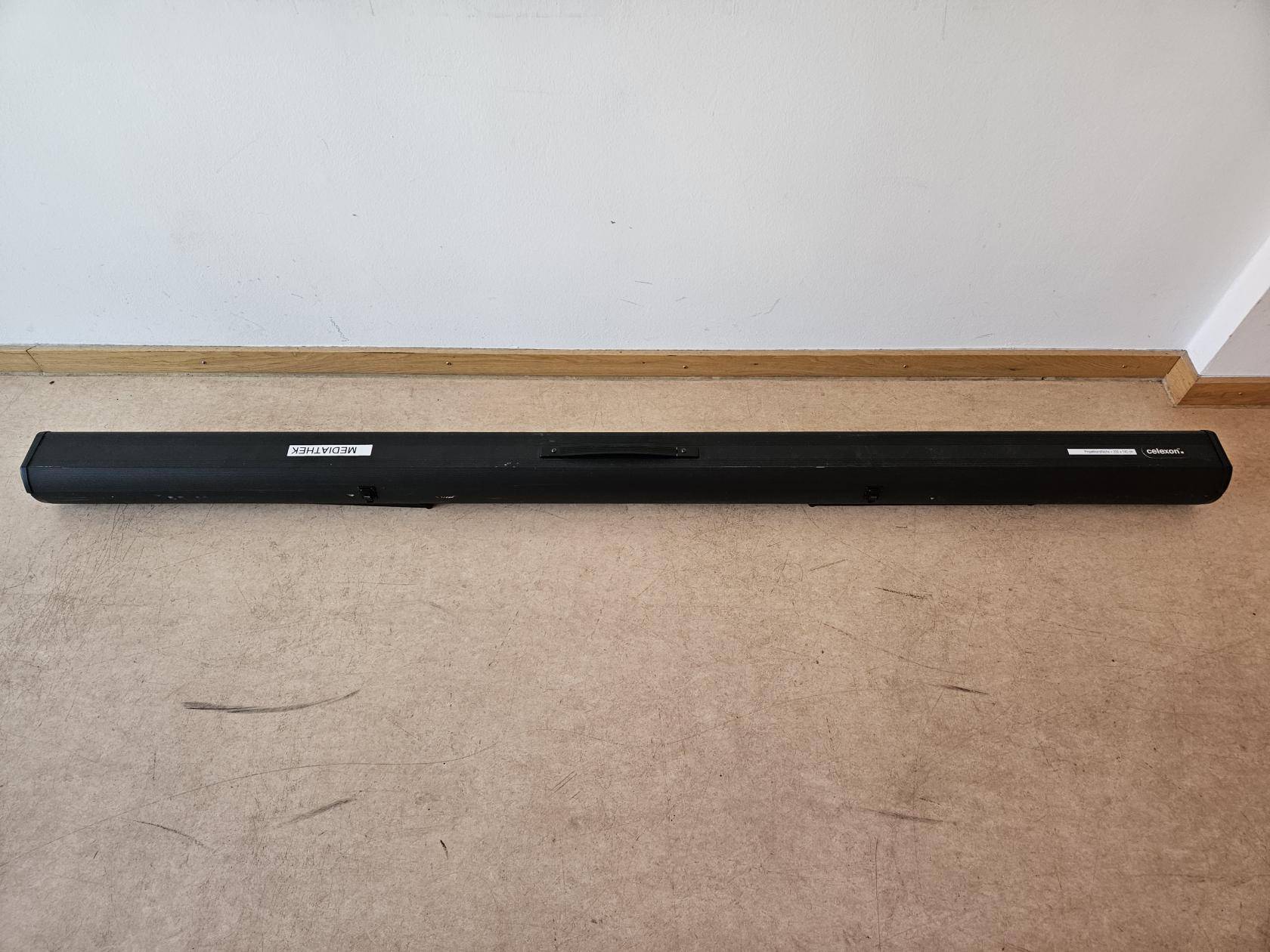 Leinwandgehäuse auf dem Boden vor einer Wand